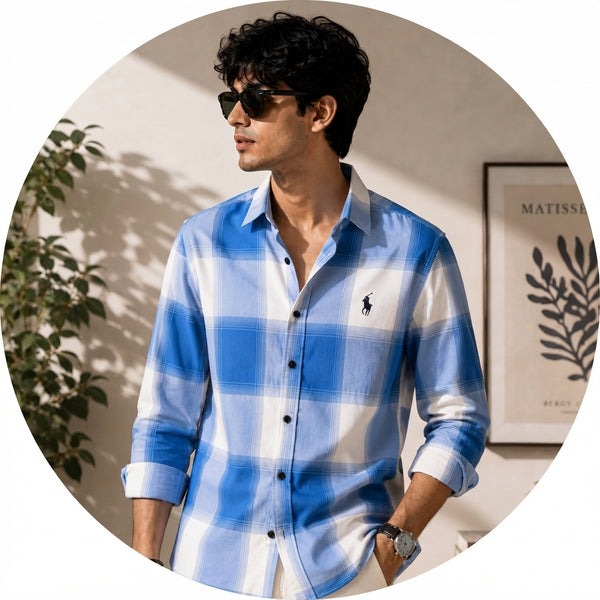 A professional portrait of Varun Varma wearing a blue and white check shirt against a clean, softly lit background.